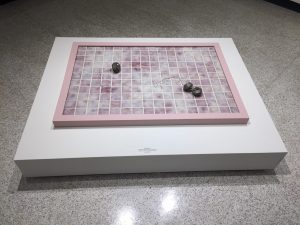 Rectangular panel that is placed on the floor. It's covered in pink tiles and has tub stoppers on top