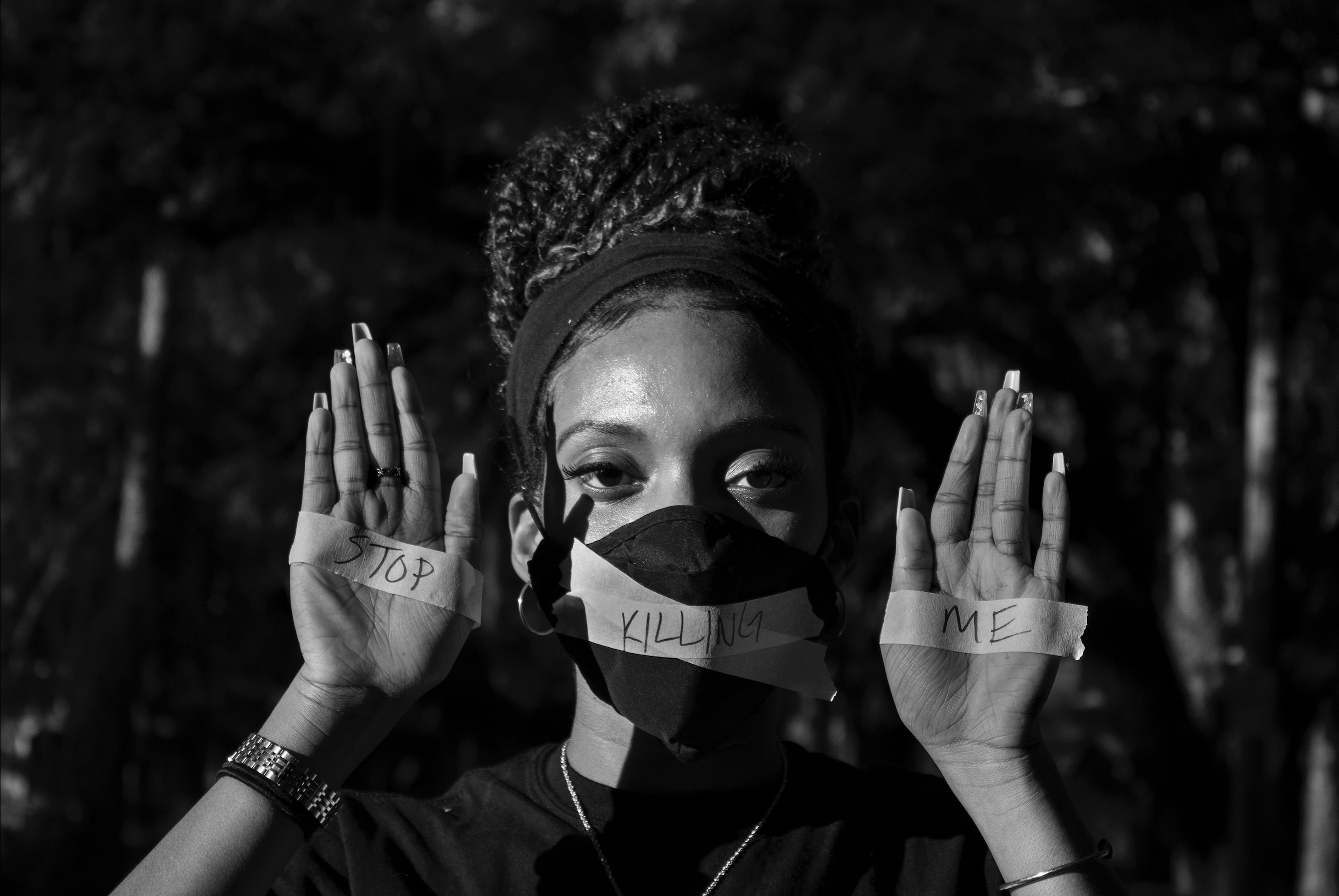 A monotype photography displaying a subject with tape over their mouth and hands with the words "Stop Killing Me".