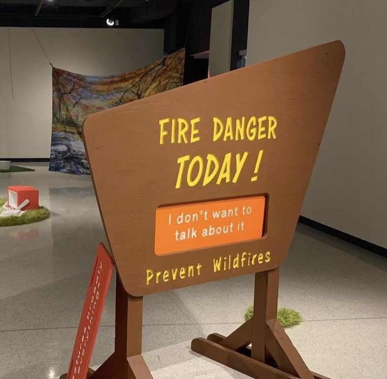 Brown four sided entry sign reading "FIRE DANGER TODAY!" and "I don't want to talk about it" in the middle with "Prevent Wildfires" on the  bottom of the sign residing in the front of the entire exhibit. 