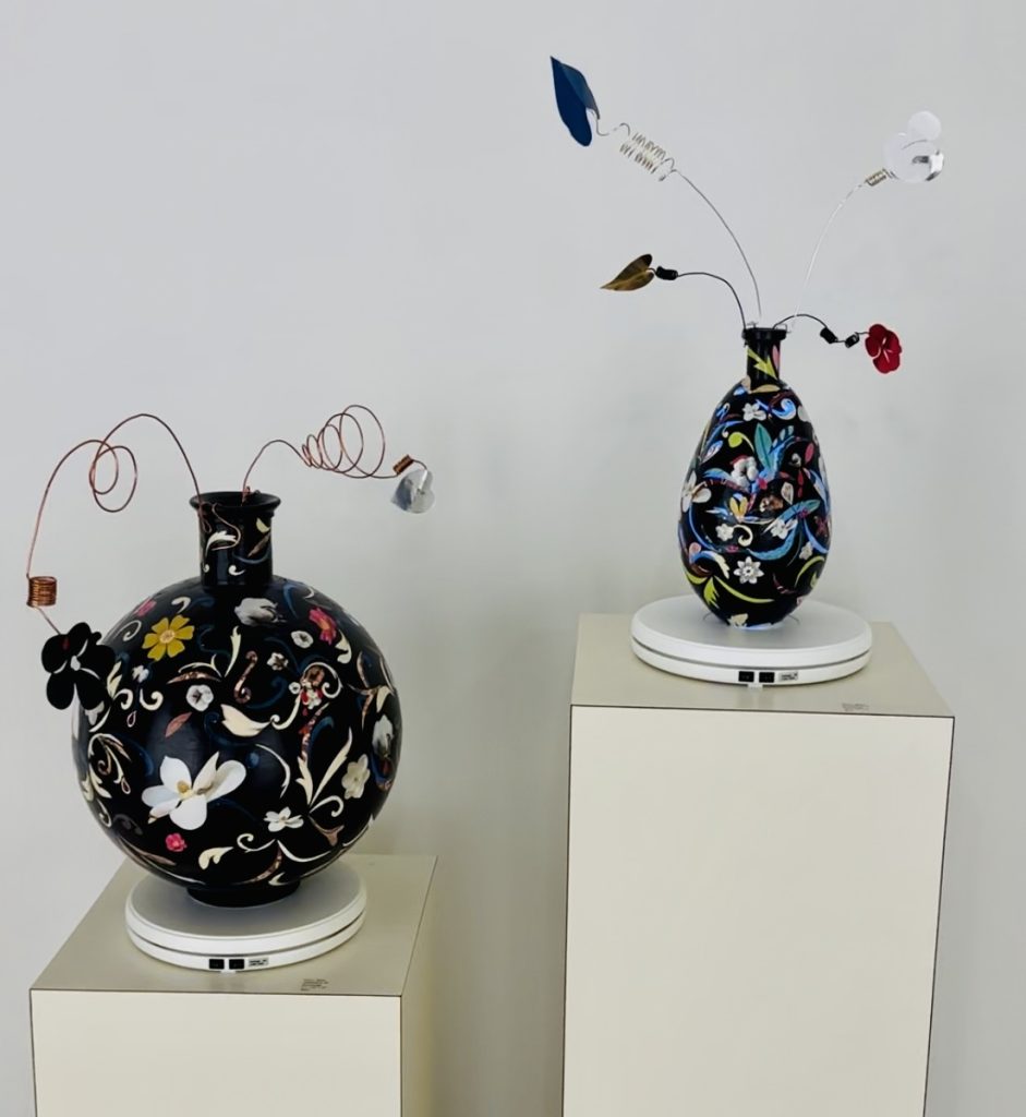 Antebellum 20 and Antebellum 29 by Paul C. Blake. Two black vase with floral designs and wires coming from the top.