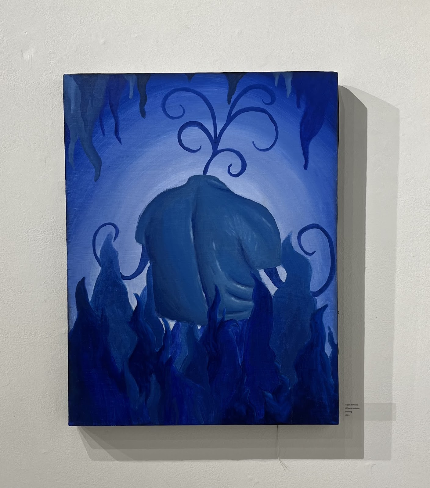 The blue body of Williams sits in a blue fiery and woodsy facing away from the viewer as sprouts grow from his arms.