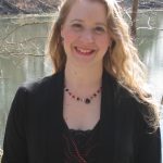 Person smiling in front of body of water