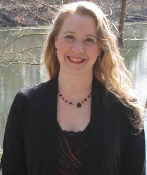Person smiling in front of body of water